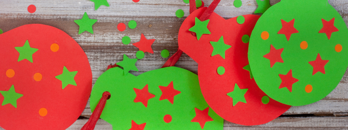 A wood table with red and green paper crafts.