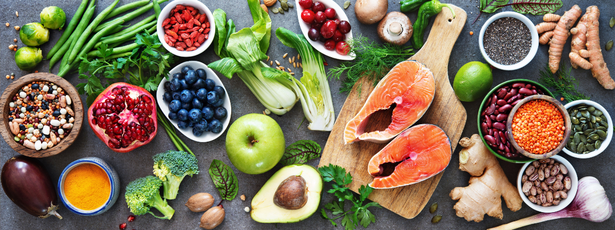 A table with a variety of fruit, vegetables, and meat spread out.