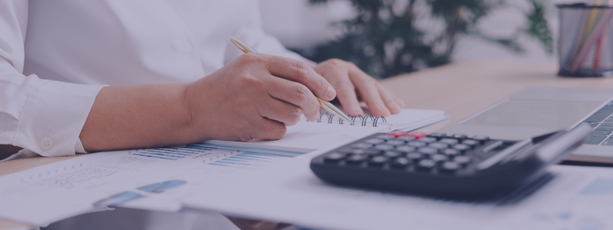 A person sits at a table with papers and a calculator.
