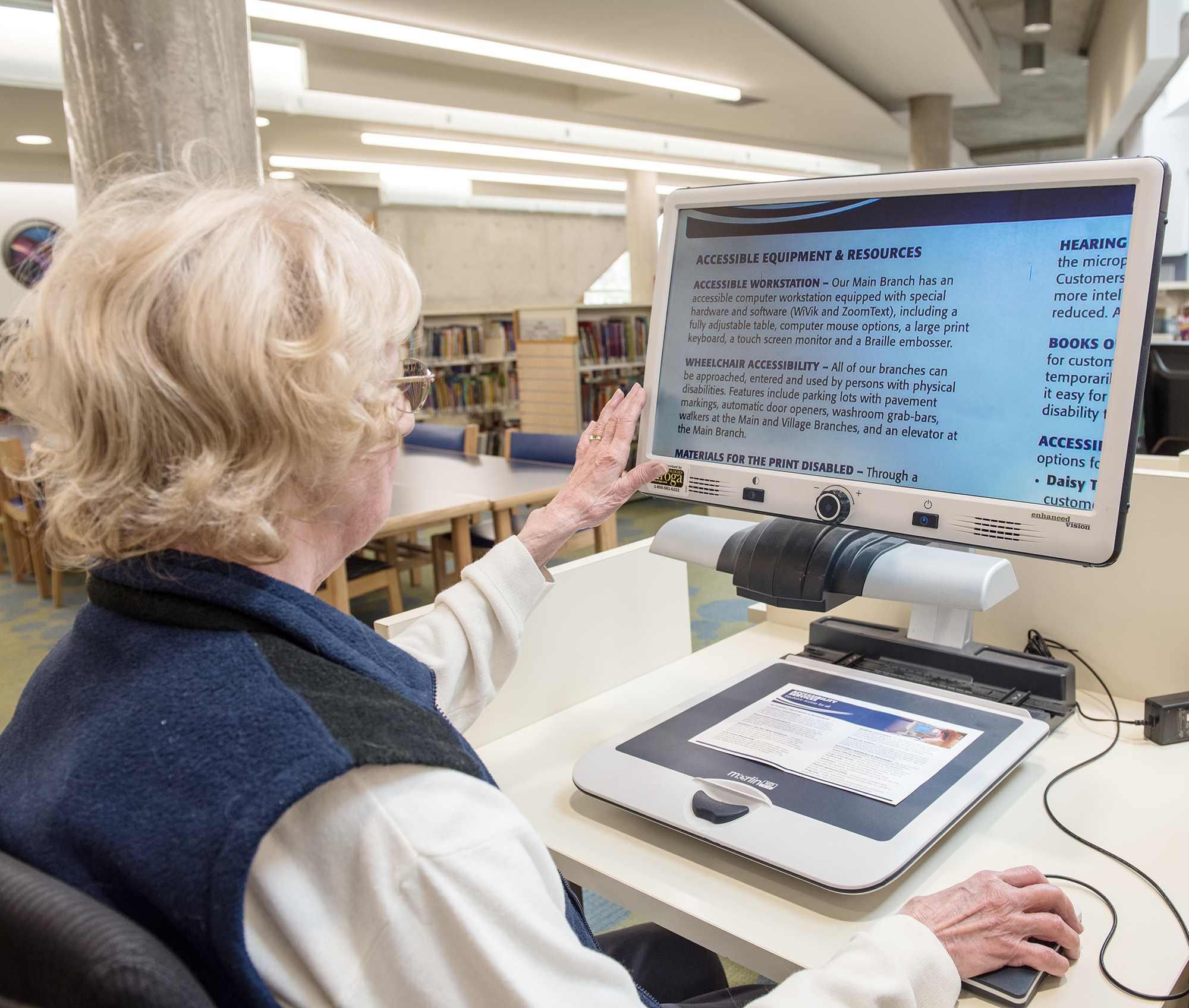 A woman with white hair uses an accessible computer at the Main Branch