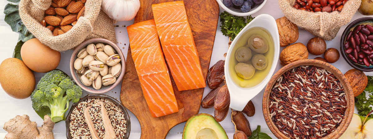 An assortment of colourful fruits and vegetables, nuts, and salmon spread out on a table.