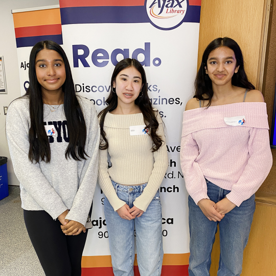 A group of teen Library volunteers stand together in the Rotary Room at Main Branch.